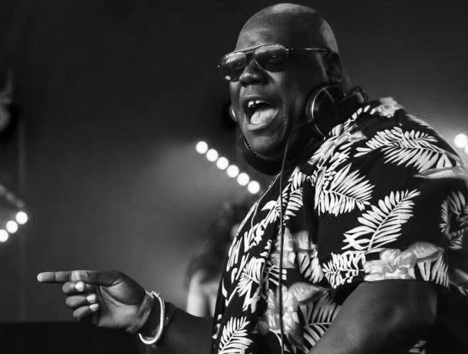 a smiling man wearing sunglasses onstage djing